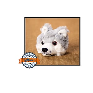 May include: Gray wolf plush toy with black nose and brown eyes. The toy is lying on a brown burlap surface.