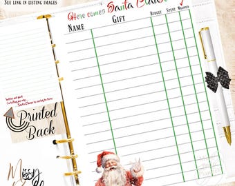 Op de afbeelding: Een planner-inlegvel met een vakantiethema en een tabel met kolommen voor Name, Gift, Budget, Spent en Wrapped. De koptekst luidt Here comes Santa Clause. Onderaan staat een illustratie van de Kerstman en een witte pen met een zwarte strik.