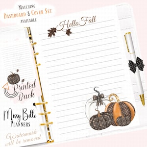 May include: A planner page featuring the text Hello Fall, decorated with brown leaf illustrations and a cluster of pumpkins with black and orange patterns. A white pen with a black bow clip is attached to the side, and a dashboard insert is visible.
