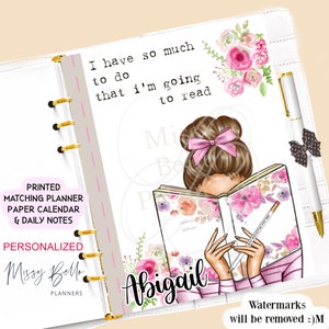 May include: A personalized planner cover featuring a woman with brown hair and a pink bow reading a book with floral designs. The text "I have so much to do that I'm going to read" is written above the woman. The text "Abigail" is written below the woman. The text "Missy Bello Planners" is written in the bottom left corner.