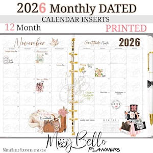 Op de afbeelding: 2026 maandelijks gedateerde kalenderinvoegsels met een 12-maanden lay-out. De gedrukte planner heeft een november spread met decoratieve elementen en de tekst "Holiday Essentials". De planner bevat een gouden pen en een zwarte strik.