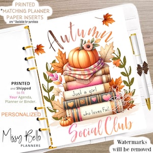 May include: A white planner cover with a fall-themed design. The design features a stack of books with a pumpkin on top, surrounded by fall leaves. The text "Autumn" is written in pink and gold lettering. The text "Just a girl who loves Fall! Social Club" is written in pink lettering.
