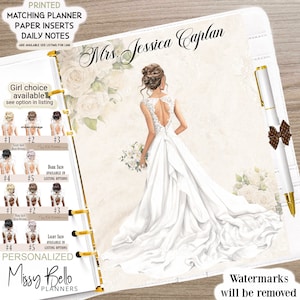 May include: A white personalized planner with a bride illustration and the text "Mrs. Jessica Caplan". The planner has a gold ring binder and includes a pen with a brown bow.