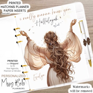 May include: A planner page featuring an illustration of a person with long wavy hair and flowing sleeves, arms raised. Text reads: i really wanna know you Hallelujah my Lord, and the name Evelyn. A white pen with gold accents is attached.