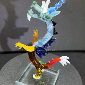 May include: A colorful glass dragon sculpture with a clear base. The dragon features shades of blue, green, yellow, and red. The text "Bamboo Treasure Land" is visible on the sculpture.