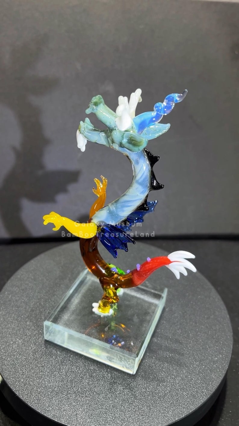May include: A colorful glass dragon sculpture with a clear base. The dragon features shades of blue, green, yellow, and red. The text "Bamboo Treasure Land" is visible on the sculpture.