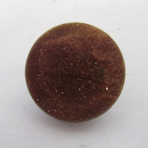 May include: A round, brown, glittery ornament with a textured surface.