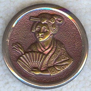 May include: A gold-toned metal button with a raised image of a woman in a traditional Japanese kimono holding a fan. The background is a reddish-brown color.