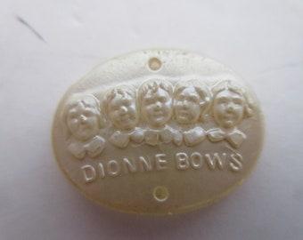 May include: A white oval button with five embossed faces of children and the text "DIONNE BOWS".