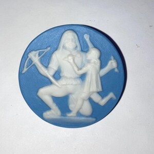 May include: A round, blue and white cameo featuring a figure with a crossbow and a child. The figures are white and the background is a solid blue. The cameo is a classic design.