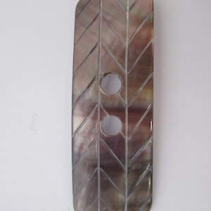 May include: A dark brown, rectangular button with a herringbone pattern and two holes. The button is made of mother of pearl.