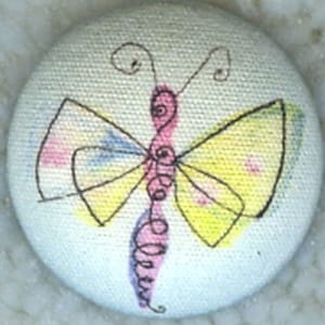 May include: A white button with a hand-painted butterfly design. The butterfly has pink, yellow, and blue wings with black outlines.