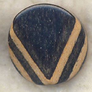 May include: A round, dark brown button with a white chevron design. The button has a textured surface.