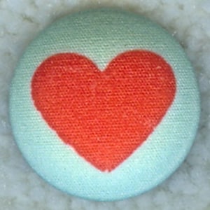 May include: A light blue button with a red heart in the center.