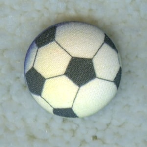May include: A white and black soccer ball button with a stitched design.
