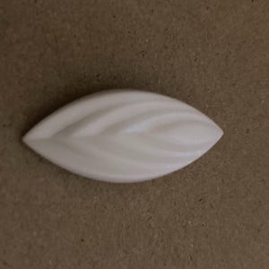 May include: A white ceramic leaf-shaped soap dish with a textured surface.