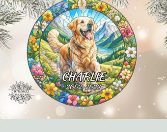 May include: A round, decorative ornament featuring a golden retriever dog in a colorful, stained-glass style design. The dog's name, "Charlie," and dates 2002-2024 are displayed. The ornament is surrounded by flowers and a mountain landscape.