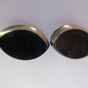 May include: A pair of black and silver earrings with a teardrop shape.