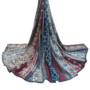 Può includere: Sciarpa drappeggiata con un design vivace. Presenta un mix di colori bordeaux, blu, arancione e bianco, con intricati motivi floreali e geometrici. I bordi sono rifiniti con un bordo scuro.