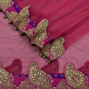 May include: A pink sheer fabric with gold and silver embroidery. The fabric has a paisley pattern and is decorated with small beads.