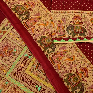 Può includere: Un tessuto color amaranto con un motivo dettagliato con elefanti, figure e disegni floreali nei toni del verde, giallo e rosa. Il tessuto ha un bordo decorativo e una striscia amaranto a tinta unita.