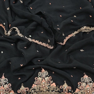 May include: A black fabric textile featuring a textured surface with scattered small peach-colored embroidered accents. The edges and bottom border are adorned with intricate metallic gold and peach floral embroidery, accented by small clear sequins.
