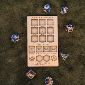 May include: A wooden Warlock Tracker with slots for spell levels, mystic arcanum, spell attack bonus, and spell DC. The tracker is surrounded by various dice with blue and gold accents.