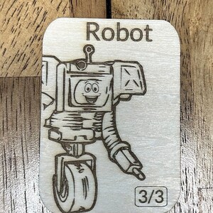 May include: A wooden card with a black and white illustration of a robot with a wheel. The card has the word "Robot" at the top and "3/3" at the bottom.