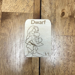 May include: A wooden card with a line drawing of a dwarf with a beard and a hat. The card says "Dwarf" and "1/1" on it.