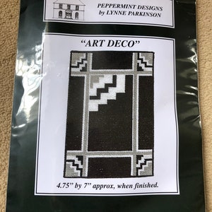 May include: A black and white cross-stitch pattern titled "Art Deco" by Lynne Parkinson. The pattern is 4.75 inches by 7 inches when finished.