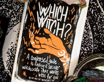 May include: A black and white illustration of a hand with the text "WHICH WITCH?" above it. The text below the hand reads "A condensed guide to finding a secular witchcraft that works best for you. By Wit Will & Witchcraft."