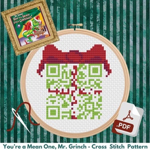 May include: A cross-stitch pattern featuring a gift box design in green and red, with a red bow. The pattern is in a wooden embroidery hoop. The image includes a framed Dr. Seuss book cover and the text "You're a Mean One, Mr. Grinch".