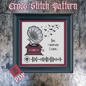 以下が含まれることがあります： 黒いフレームに入ったクロスステッチパターン。デザインは、灰色の蓄音機、音符、コウモリが特徴です。「The Vampire Song」というテキストとSpotifyコードが含まれています。隅には「PDF」と書かれた小さな赤いカードがあります。