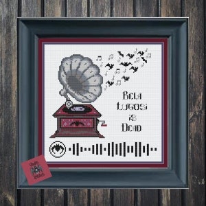 以下が含まれることがあります： 額縁に入ったクロスステッチアート。ヴィンテージの蓄音機のデザインで、音符とコウモリのシルエット、そして「Bela Lugosi is Dead」の文字が描かれています。QRコードと小さな「Goth Stitch」のタグも表示されています。