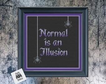 May include: A black framed cross-stitch with purple embroidery. The cross-stitch features the text "Normal is an Illusion" with small spider silhouettes hanging from the top.
