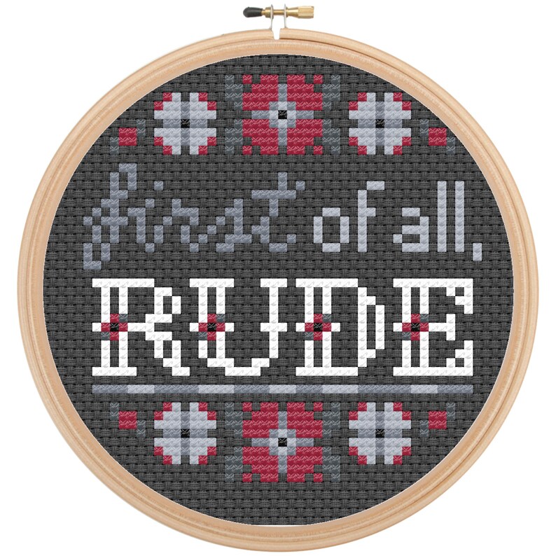 May include: A black and white cross-stitch embroidery hoop with the text "First of all, rude." in gray and white lettering. The hoop is decorated with a red and white geometric pattern.