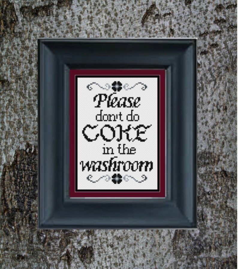May include: A framed sign with a white background and black text that reads "Please don't do coke in the washroom". The frame is black with a maroon mat.