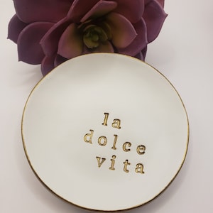 White trinket dish with a gold rim and the words "la dolce vita" written in gold lettering.  Would make a perfect gift for an Italian Wedding Engagement Gift.