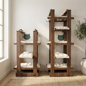 May include: Two wooden cat trees with multiple levels and cream-coloured cushions. The cat trees have a dark brown finish and feature a cat-shaped logo with the letters "W.L.O." on a green background. Designed for indoor use, they offer a climbing structure.