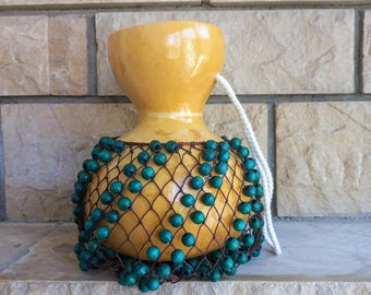 タカラガイの殻でできたひょうたんのシェケレ：白いビーズで飾られた