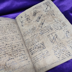 Può includere: Un libro aperto con pagine invecchiate e ingiallite piene di note scritte a mano e diagrammi geometrici in inchiostro nero. Il libro è aperto su una superficie viola.