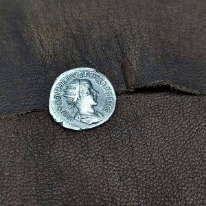 Puede incluir: Una moneda de plata con el perfil de una persona con una corona. La moneda tiene la inscripción "GORDIANVS SP", que probablemente sea el nombre de un emperador romano.