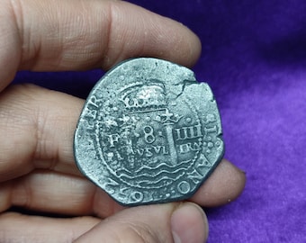 May include: A silver coin with a crown and the text "F 8 III" on it. The coin is slightly damaged and has a worn surface.