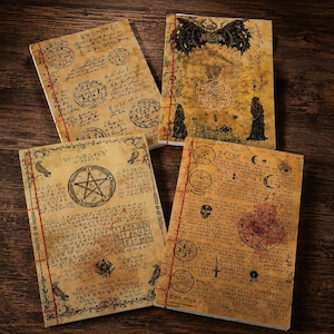 Puede incluir: Cuatro cuadernos de estilo vintage con papel envejecido y costuras rojas. Cada cuaderno presenta símbolos ocultos, ilustraciones y texto manuscrito. Las cubiertas muestran una variedad de diseños, incluyendo un pentagrama, una calavera y una criatura alada.