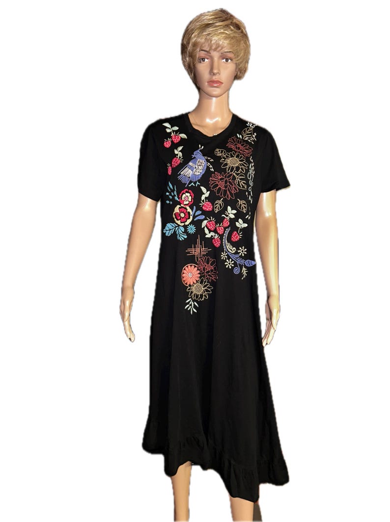 Puede incluir: Un vestido midi negro de manga corta con cuello redondo y dobladillo con volantes. La parte delantera del vestido est&aacute; decorada con bordados coloridos que representan un p&aacute;jaro azul, fresas rojas y varios motivos florales en tonos naranja, amarillo y blanco.