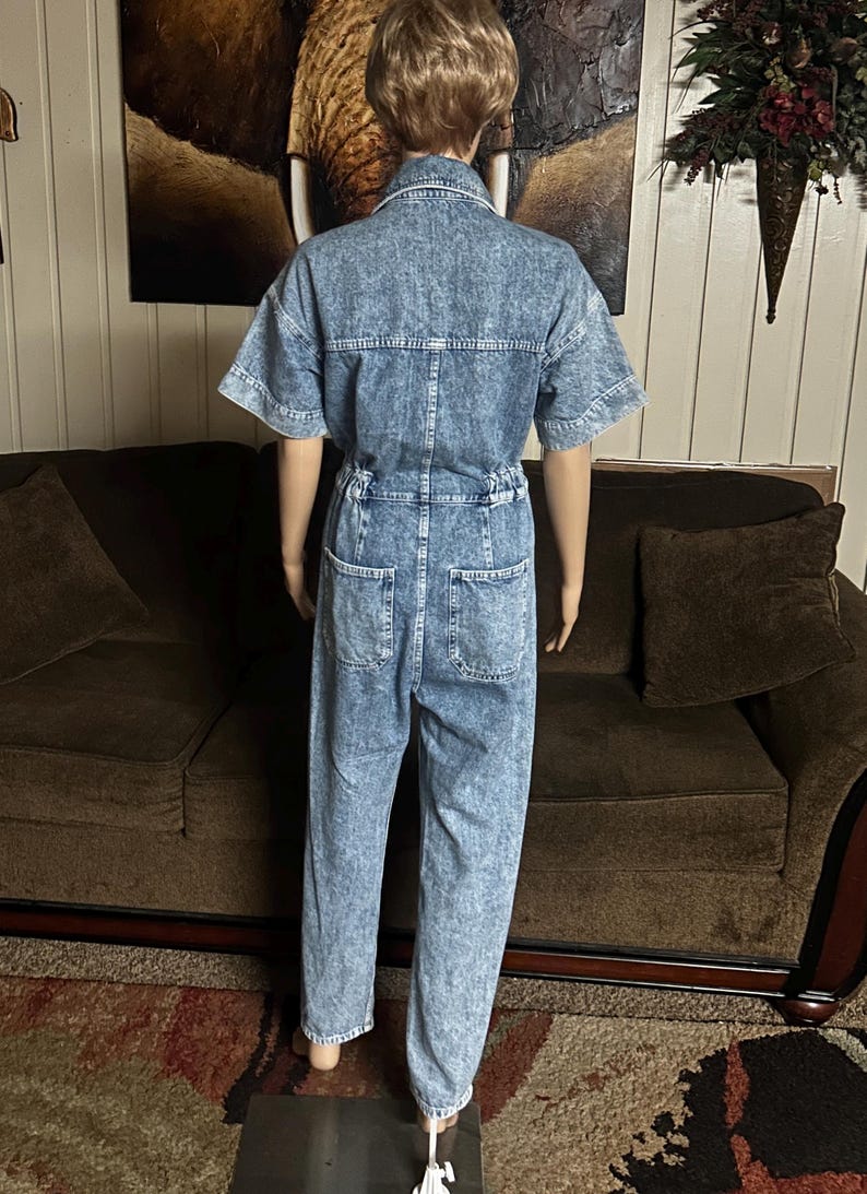 Peut inclure: Une combinaison en jean bleu clair &agrave; manches courtes et &agrave; fermeture boutonn&eacute;e. La combinaison a une coupe d&eacute;contract&eacute;e et un aspect l&eacute;g&egrave;rement d&eacute;lav&eacute;.