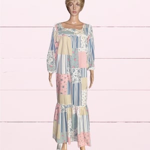 May include: A long-sleeved floor-length nightgown featuring a patchwork design with alternating panels of light blue stripes, solid cream, and floral patterns in pink, blue, and white. The garment has a square neckline with white lace trim.
