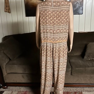 May include: A sleeveless jumpsuit with a floral pattern in shades of brown, orange, and white. The jumpsuit has a wide leg and a fitted bodice.
