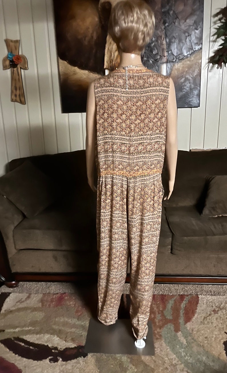 May include: A sleeveless jumpsuit with a floral pattern in shades of brown, orange, and white. The jumpsuit has a wide leg and a fitted bodice.