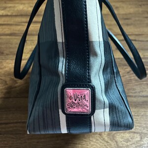 May include: A black and white striped tote bag with a black leather trim and a silver and pink logo that reads "Vera Brighton".